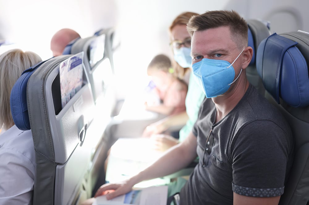 A family of three wearing masks while seated on a plane