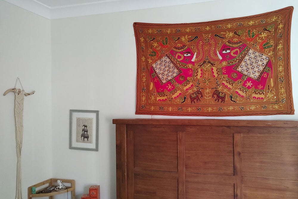 Elephant tapestry above wooden bedframe Elephant tapestry above wooden bedframe