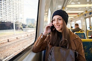 Woman smiling while holding her phone to her ear on the train Woman smiling while holding her phone to her ear on the train